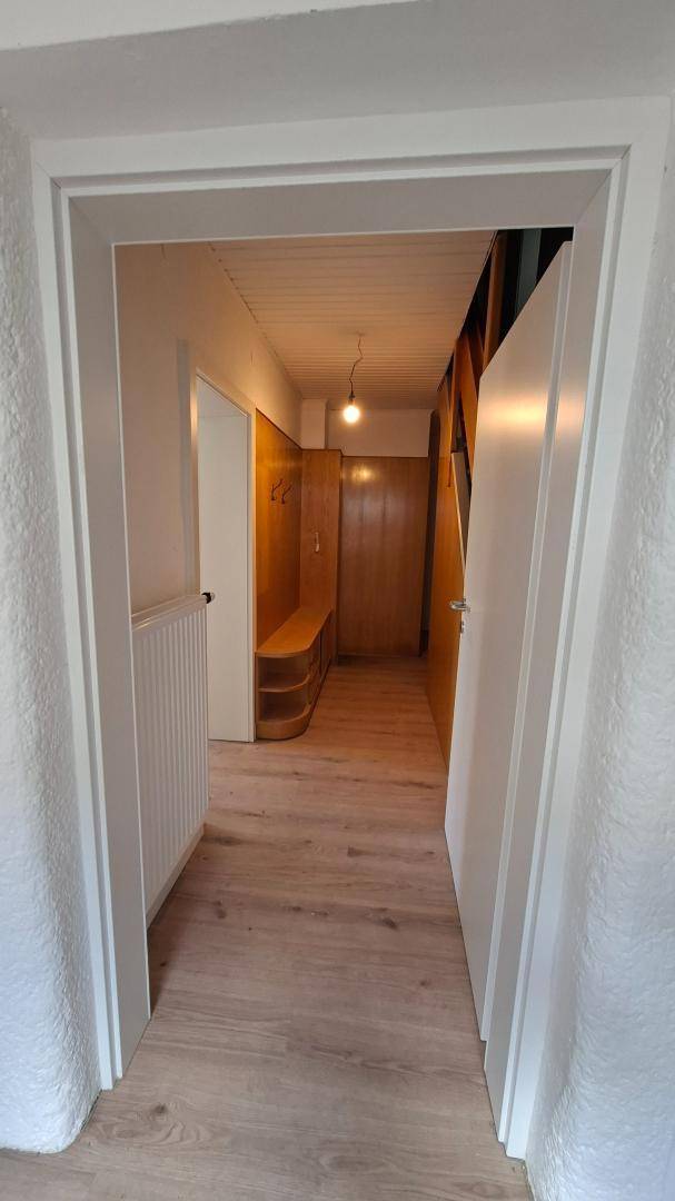 Heller Flur mit Holzvertäfelung, Holzboden und Garderobenbereich.