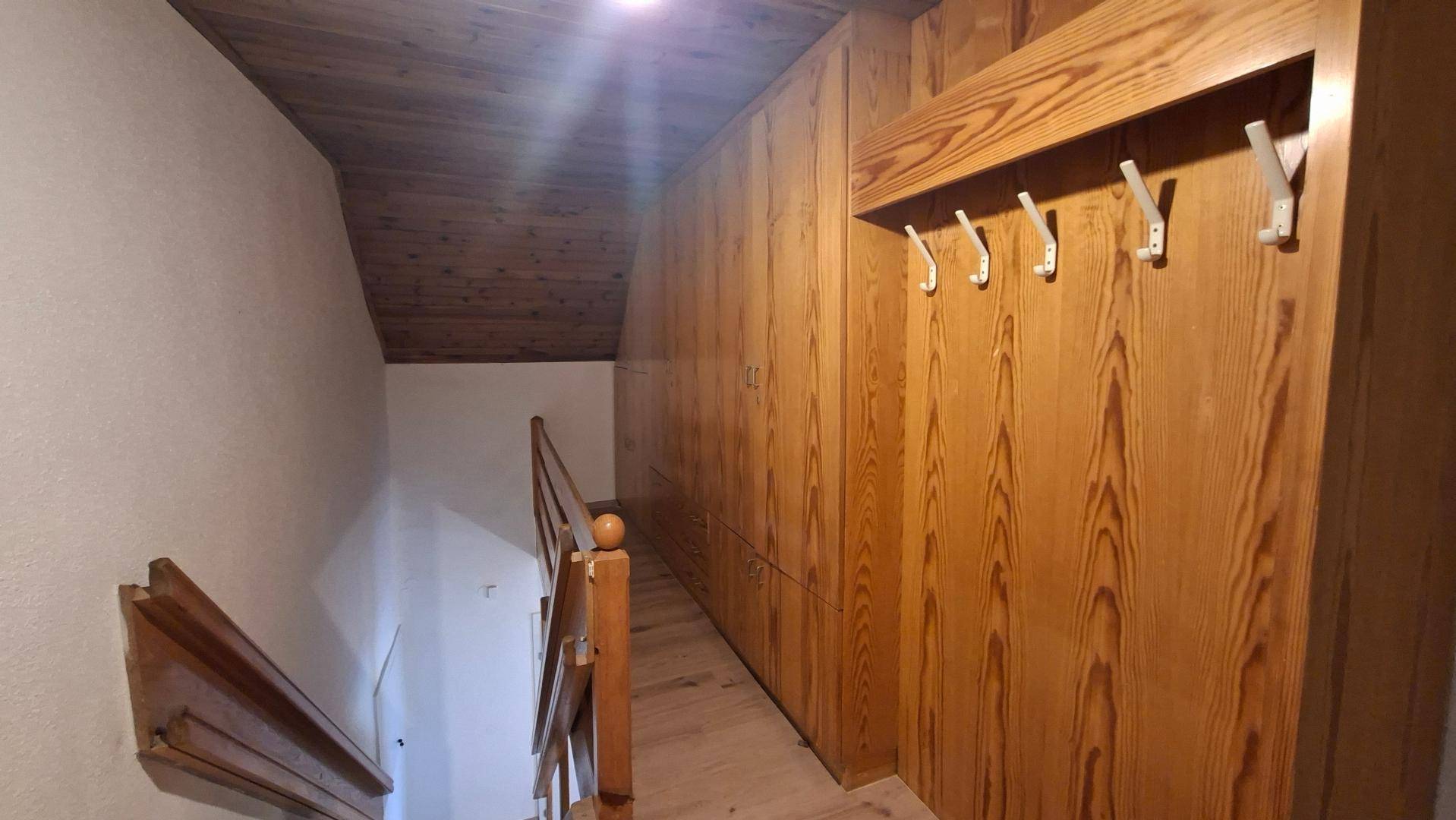 Flur im Dachgeschoss mit Holzvertäfelung, Einbauschränken und Treppenaufgang.