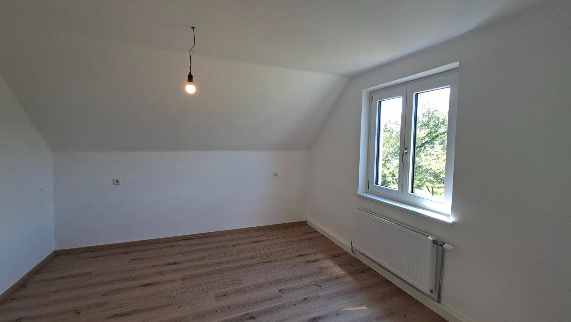 Helles Schlafzimmer im Dachgeschoss mit Laminatboden, Dachschräge und Fenster.