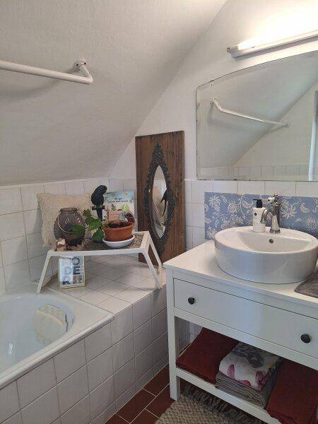 Badezimmer im Dachgeschoss mit Badewanne, Waschbecken und schräger Decke.