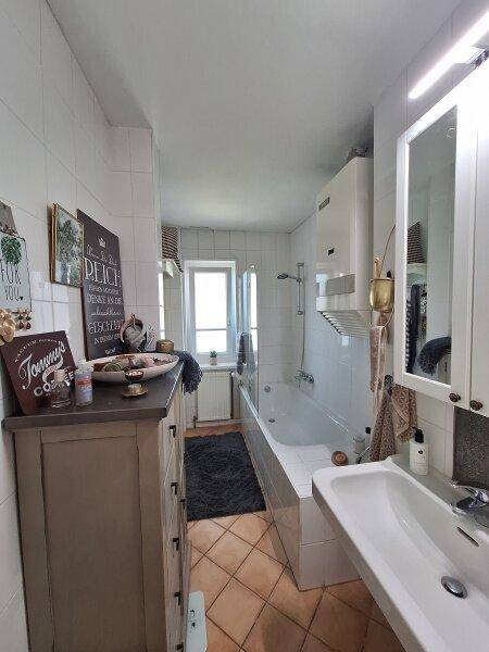 Funktionales Badezimmer mit Badewanne, Waschbecken und Spiegelschrank, hell gefliest.