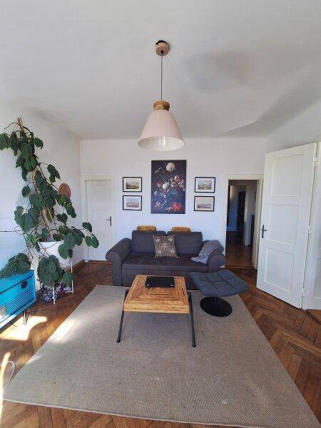 Gemütliches Wohnzimmer mit Sofa, Holztisch und Parkettboden, hell und einladend.