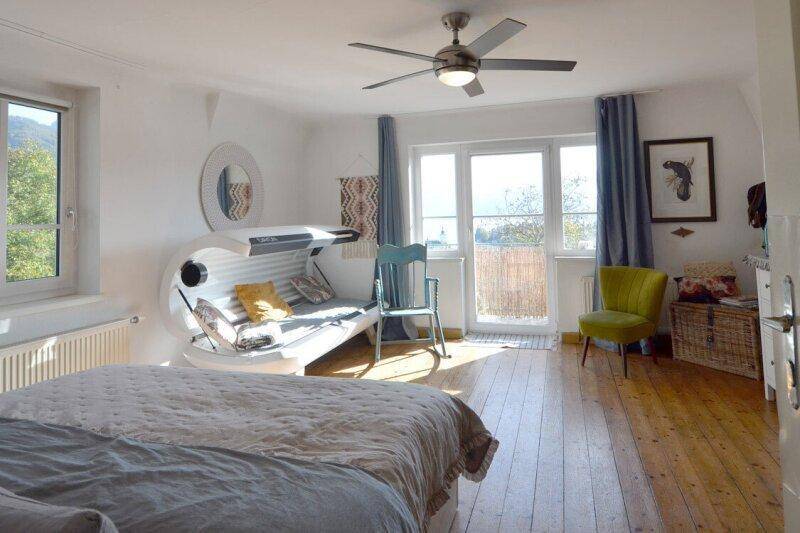 Helles Schlafzimmer mit Holzboden, Deckenventilator und Zugang zu einem französischen Balkon.