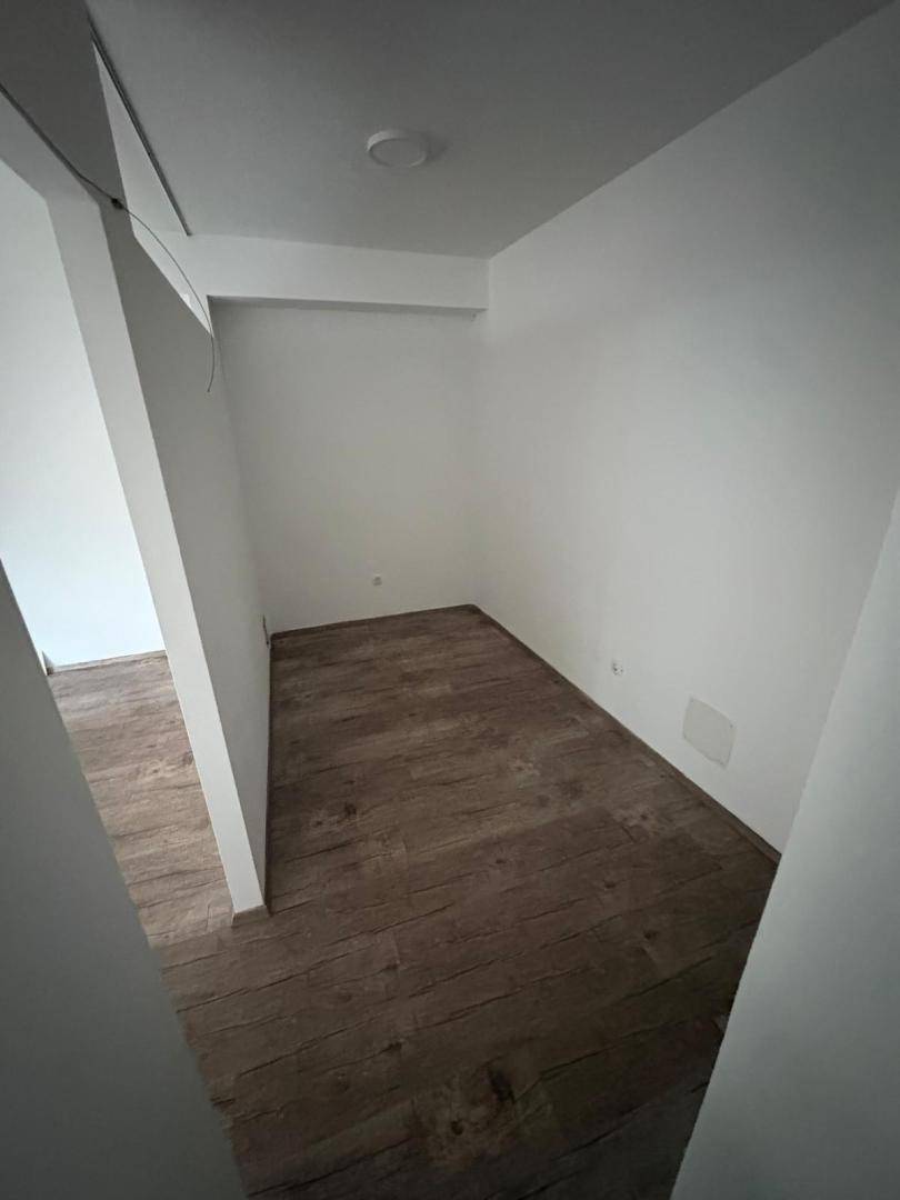 Kleiner, leerer Raum oder Nische mit dunklem Laminatboden und weißen Wänden, gut beleuchtet.