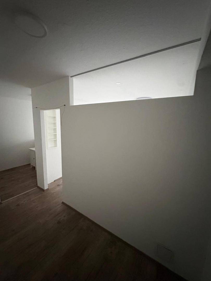 Innenansicht eines Raumes mit einer Trennwand und dunklem Laminatboden, der zwei Bereiche abgrenzt.