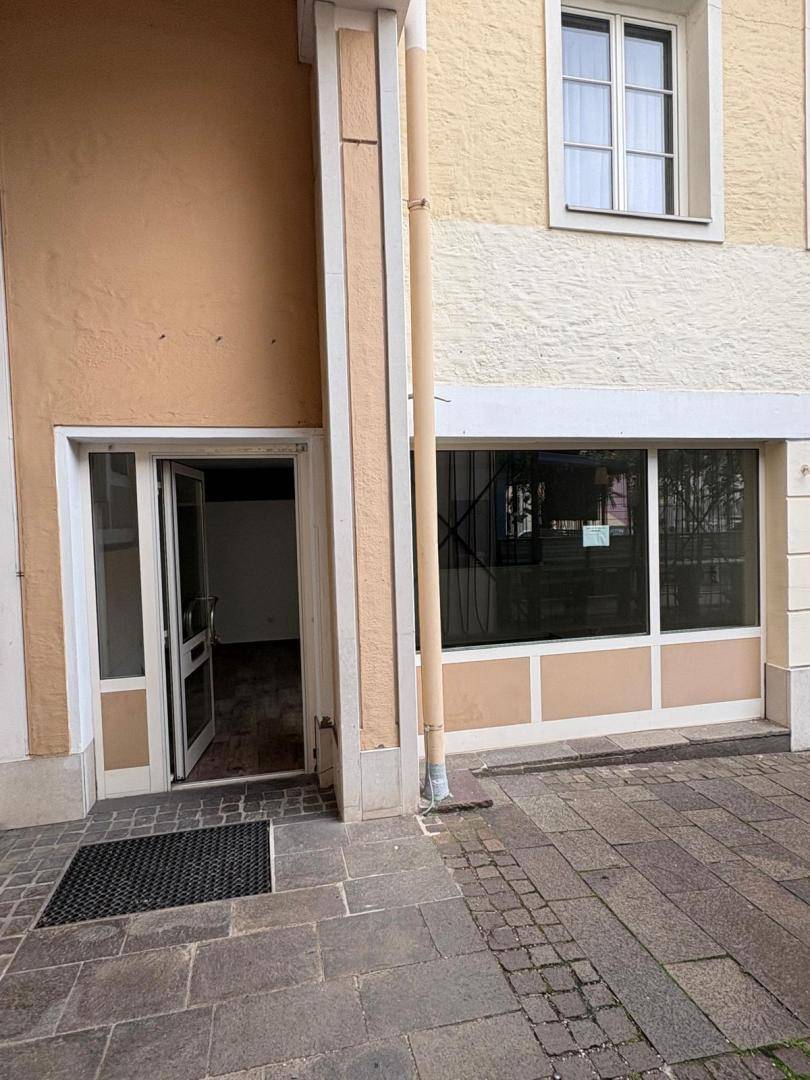 Gebäudefassade mit geöffneter Eingangstür, die einen Blick ins Innere des Raumes freigibt.