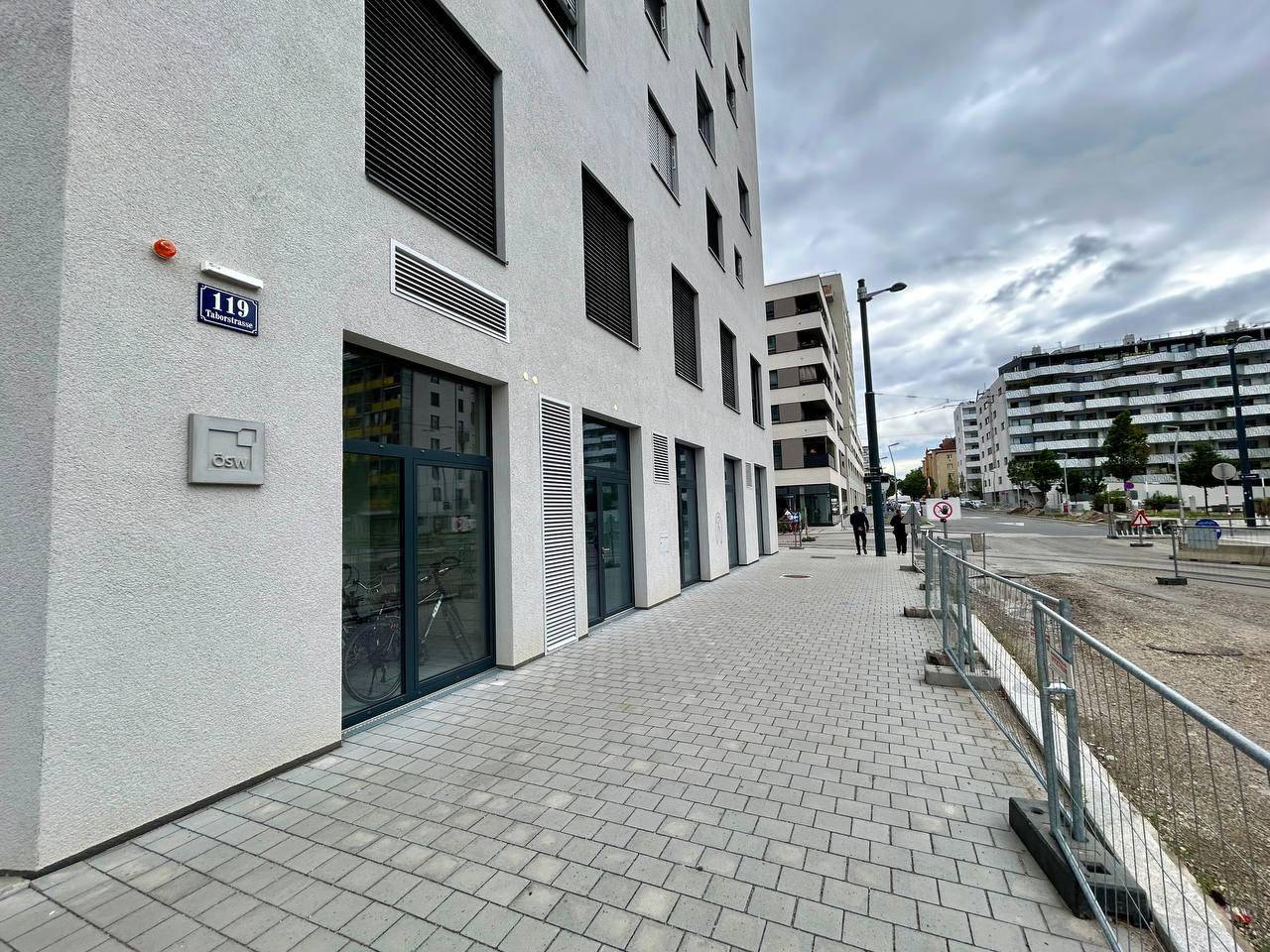 Ansicht der modernen Gebäudefassade mit Schaufenstern und dem angrenzenden Bürgersteig.