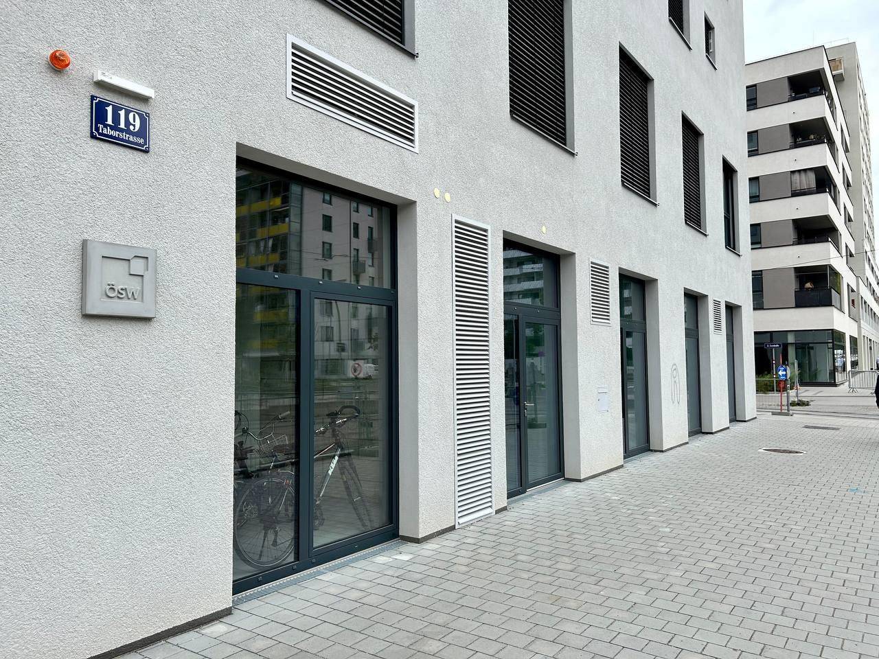 Moderne Gebäudefassade im Erdgeschoss mit großen Schaufenstern und Eingangstüren.