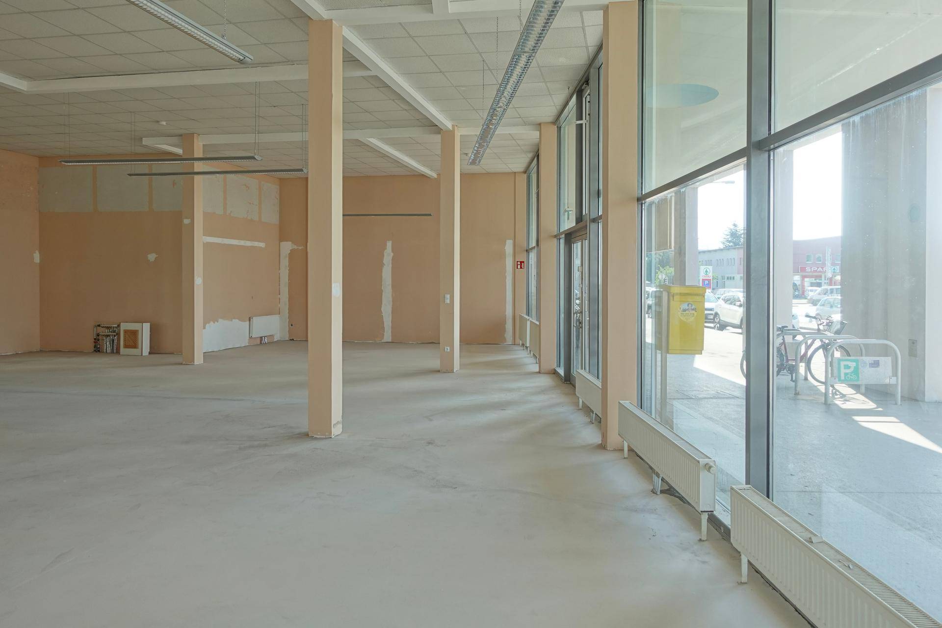 Heller Gewerberaum mit großen Fensterfronten, Säulen und Blick auf die Straße.