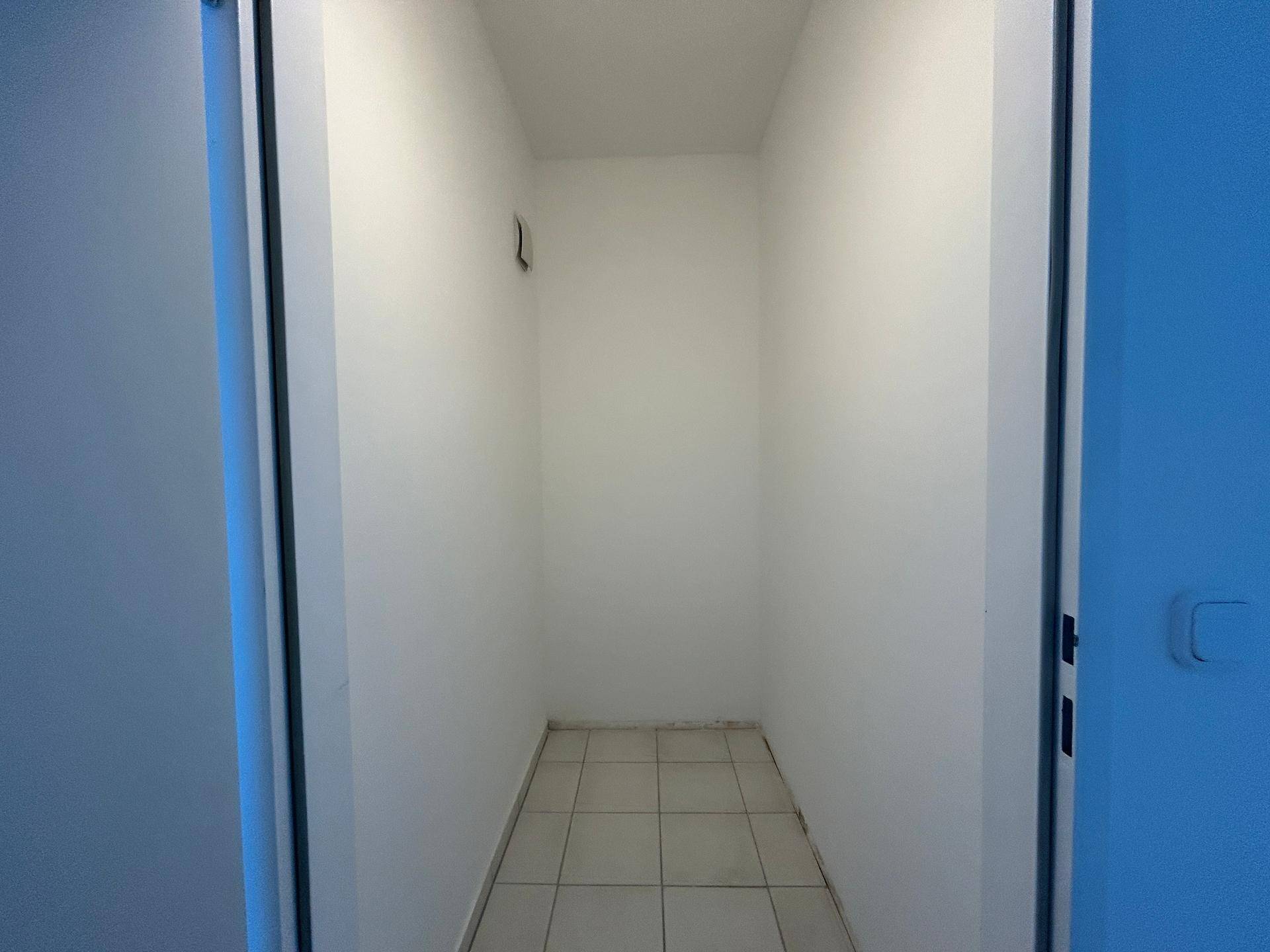 Kleiner Abstellraum mit weißen Wänden und Fliesen, ideal für zusätzlichen Stauraum.