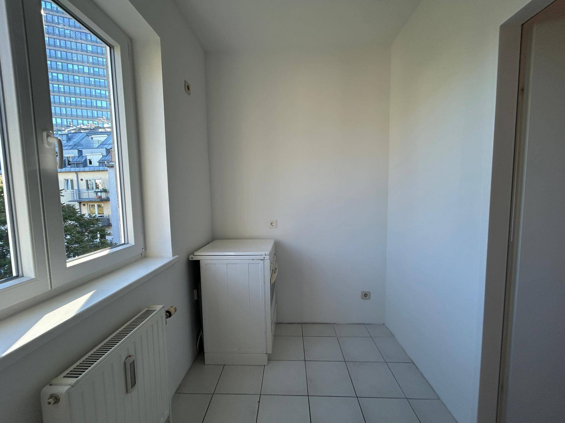 Kleiner Raum mit Fenster, Heizung und einem Schrank, möglicherweise eine Küchenzeile oder Abstellraum.