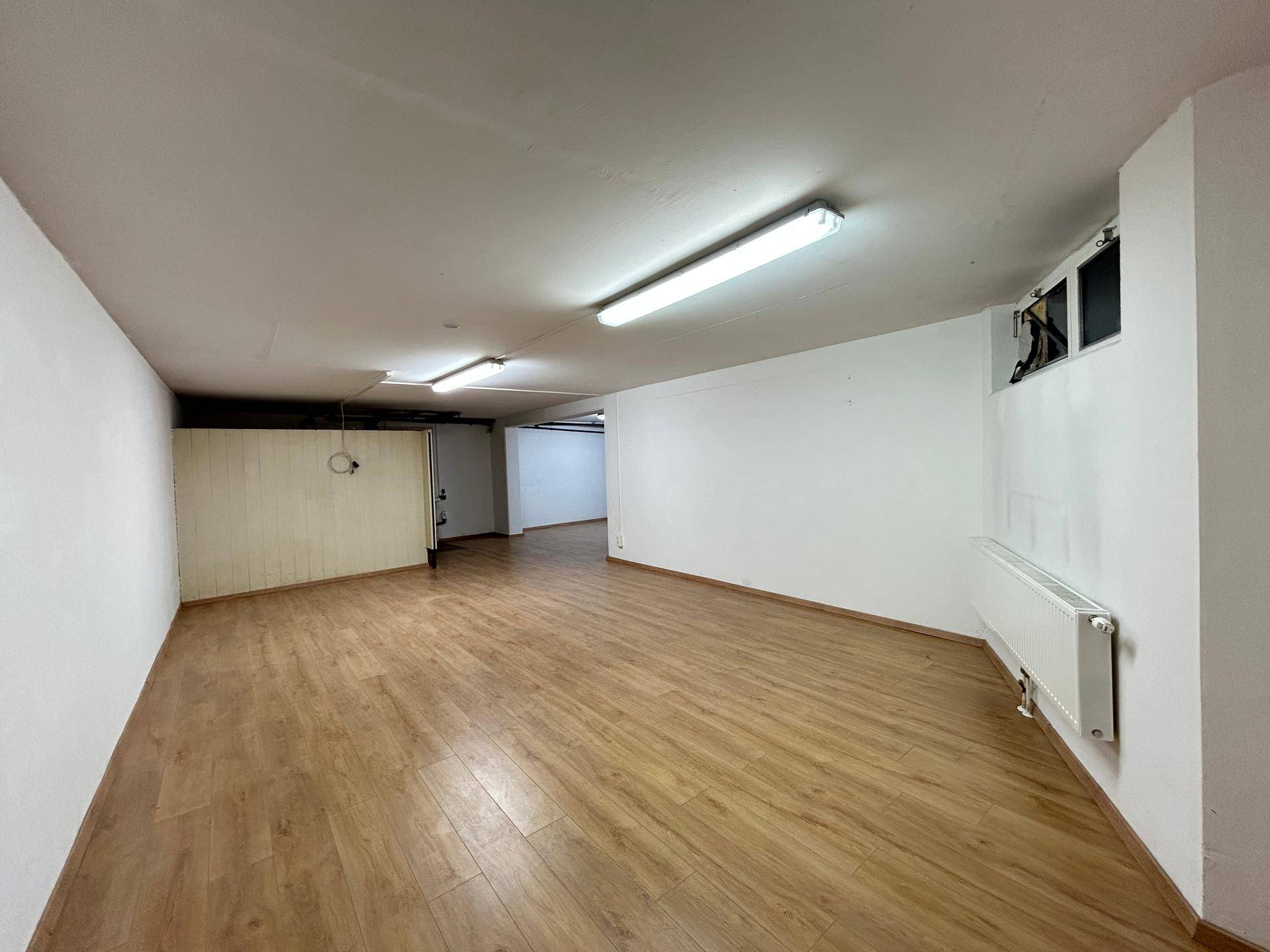 Großer Lagerraum mit Laminatboden und Heizkörper an der Wand, bietet viel Platz für verschiedene Zwecke.