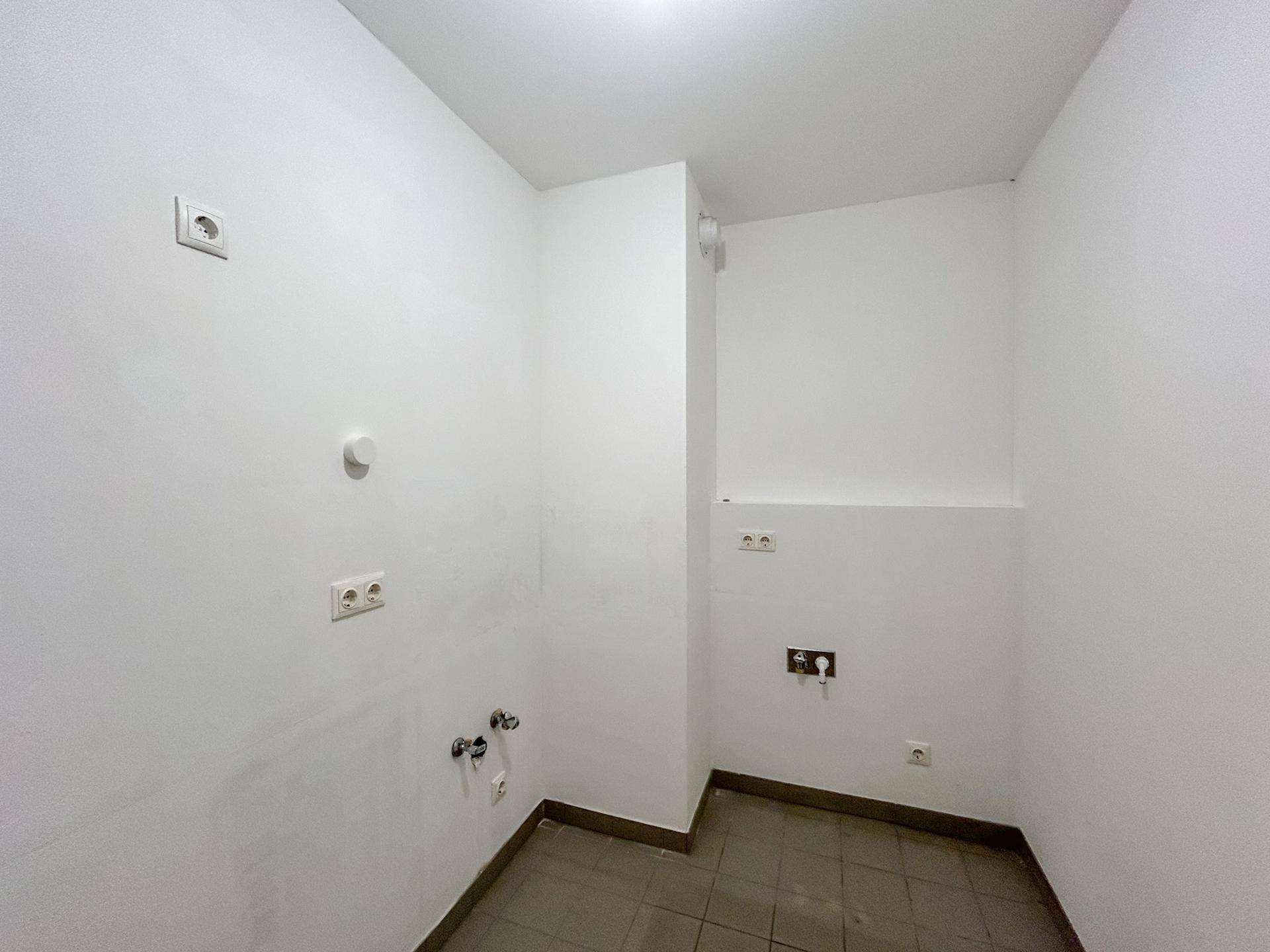 Kleiner Hauswirtschaftsraum mit Fliesenboden, Wasseranschlüssen und Steckdosen für Geräte.