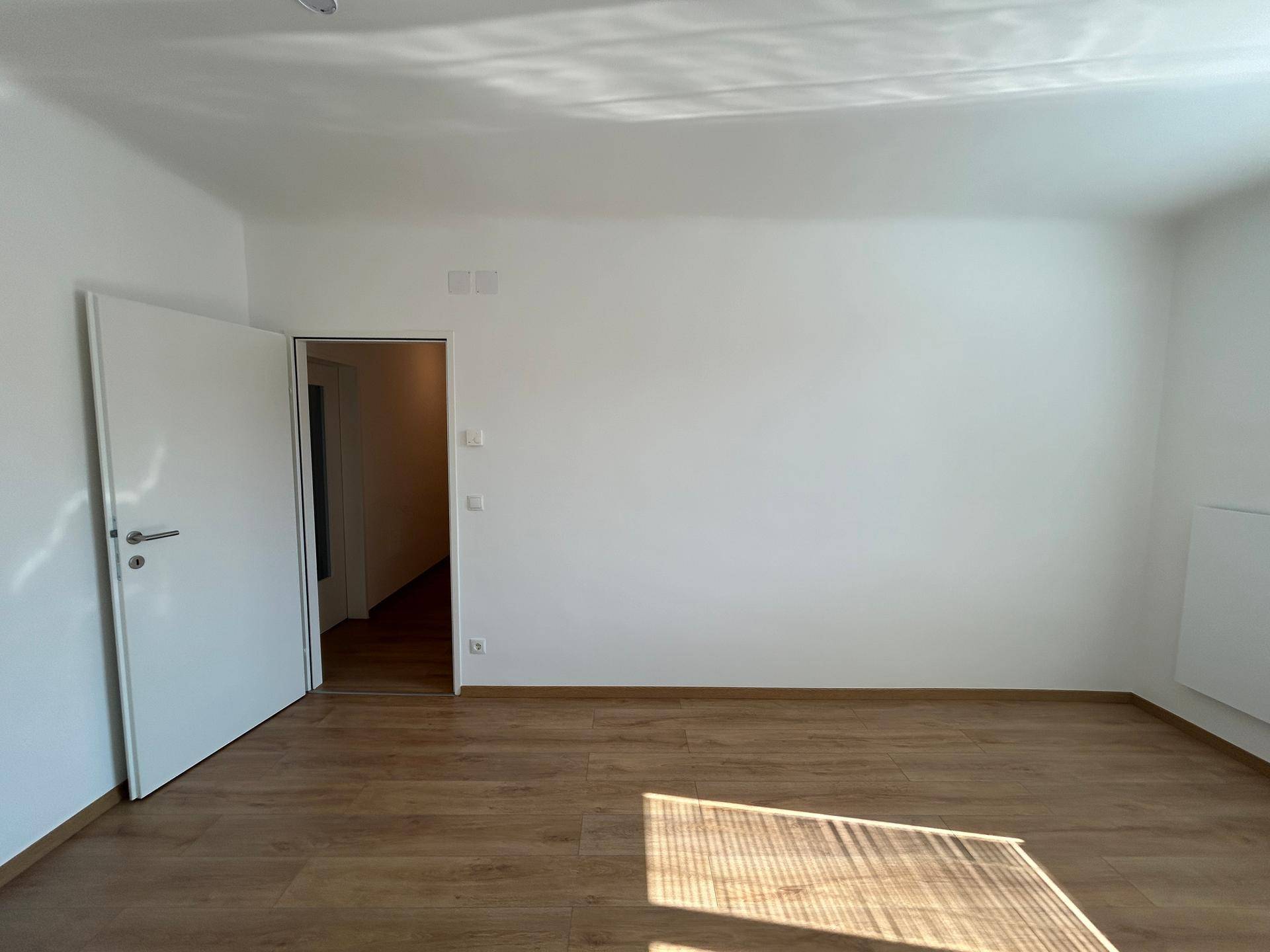 Geräumiges Schlafzimmer mit Holzboden und weiß gestrichenen Wänden, bereit zur individuellen Gestaltung.