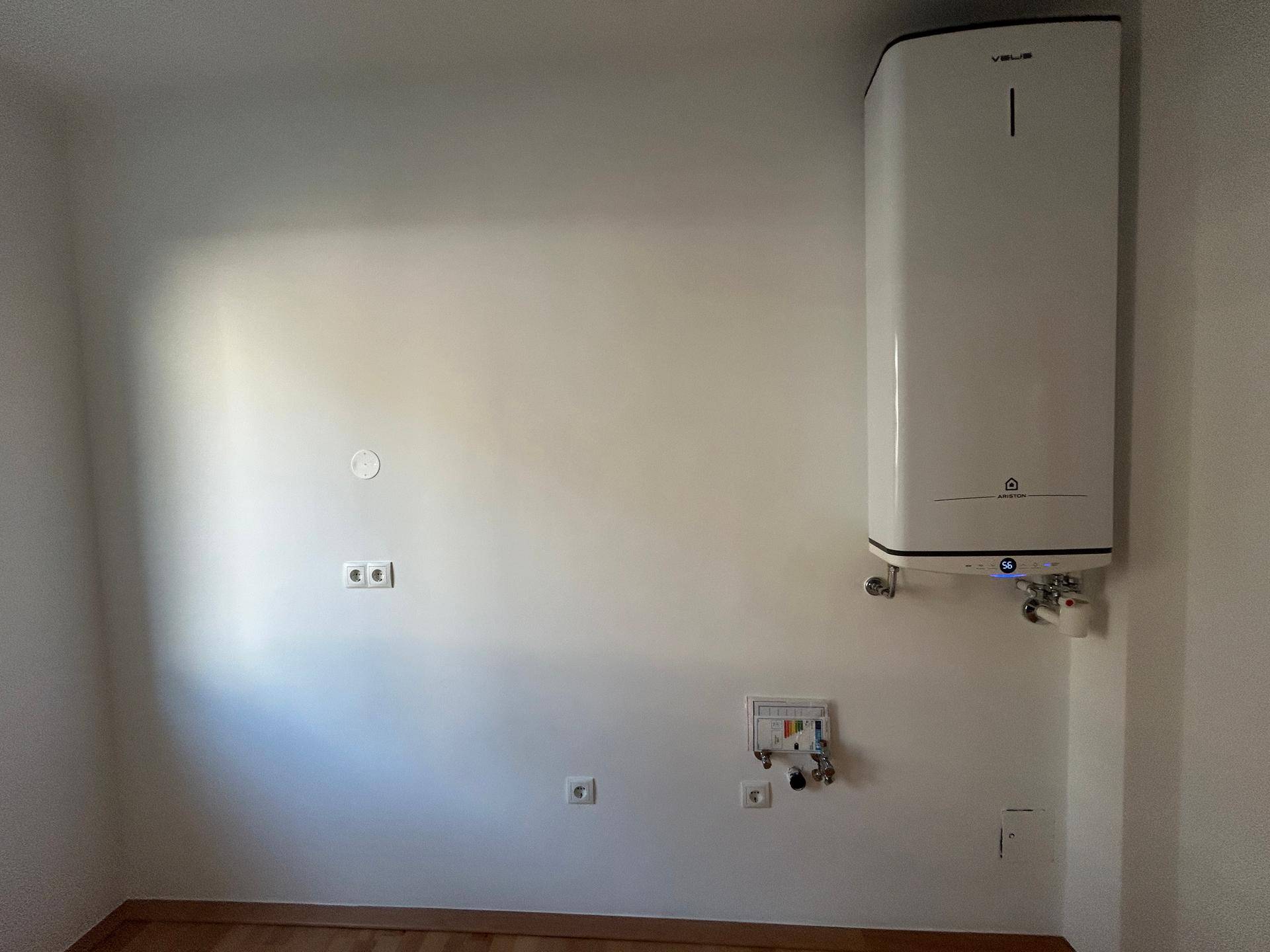 Hauswirtschaftsraum mit an der Wand montiertem Warmwasserbereiter und Anschlüssen.