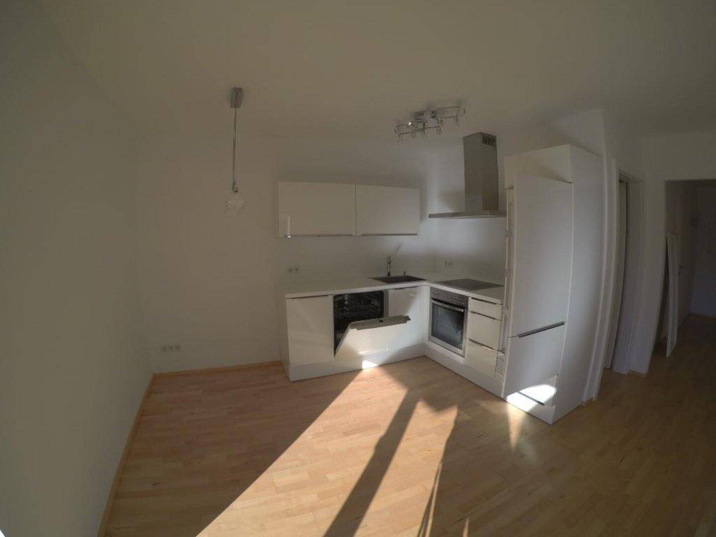 Moderne Einbauküche in Weiß mit integrierten Geräten und hellem Holzboden.
