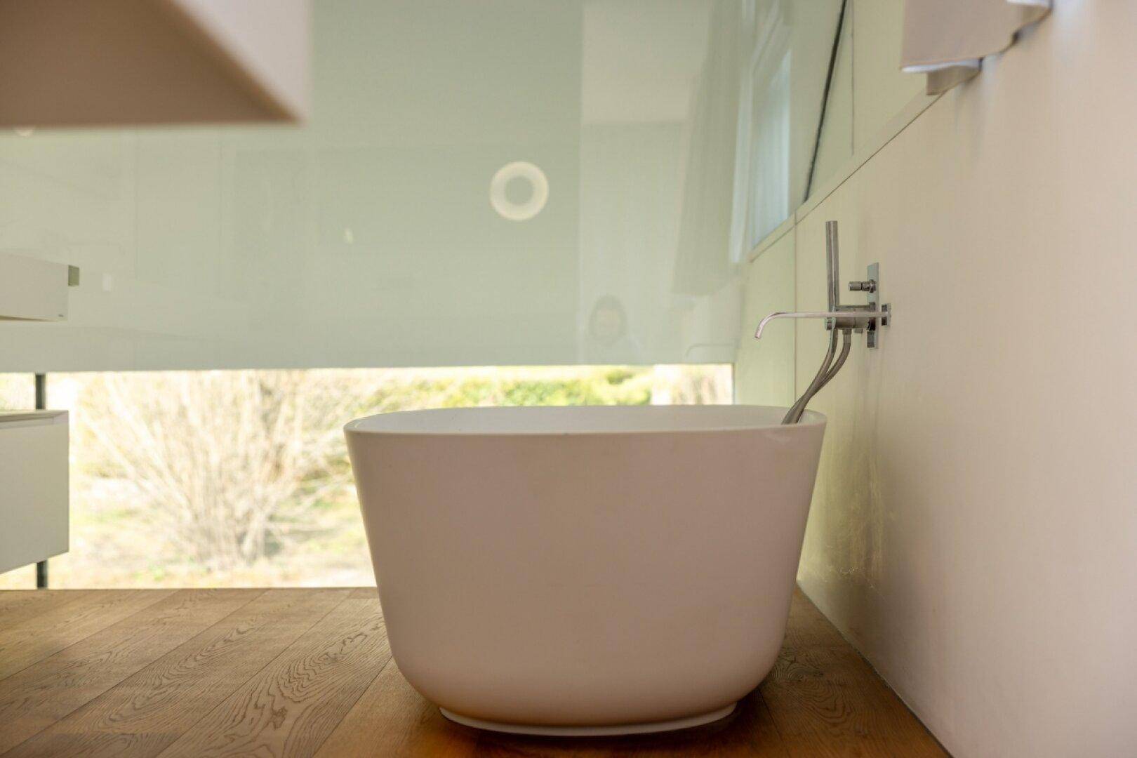 Modernes Badezimmer mit freistehender Badewanne und großem Fenster für viel Tageslicht.