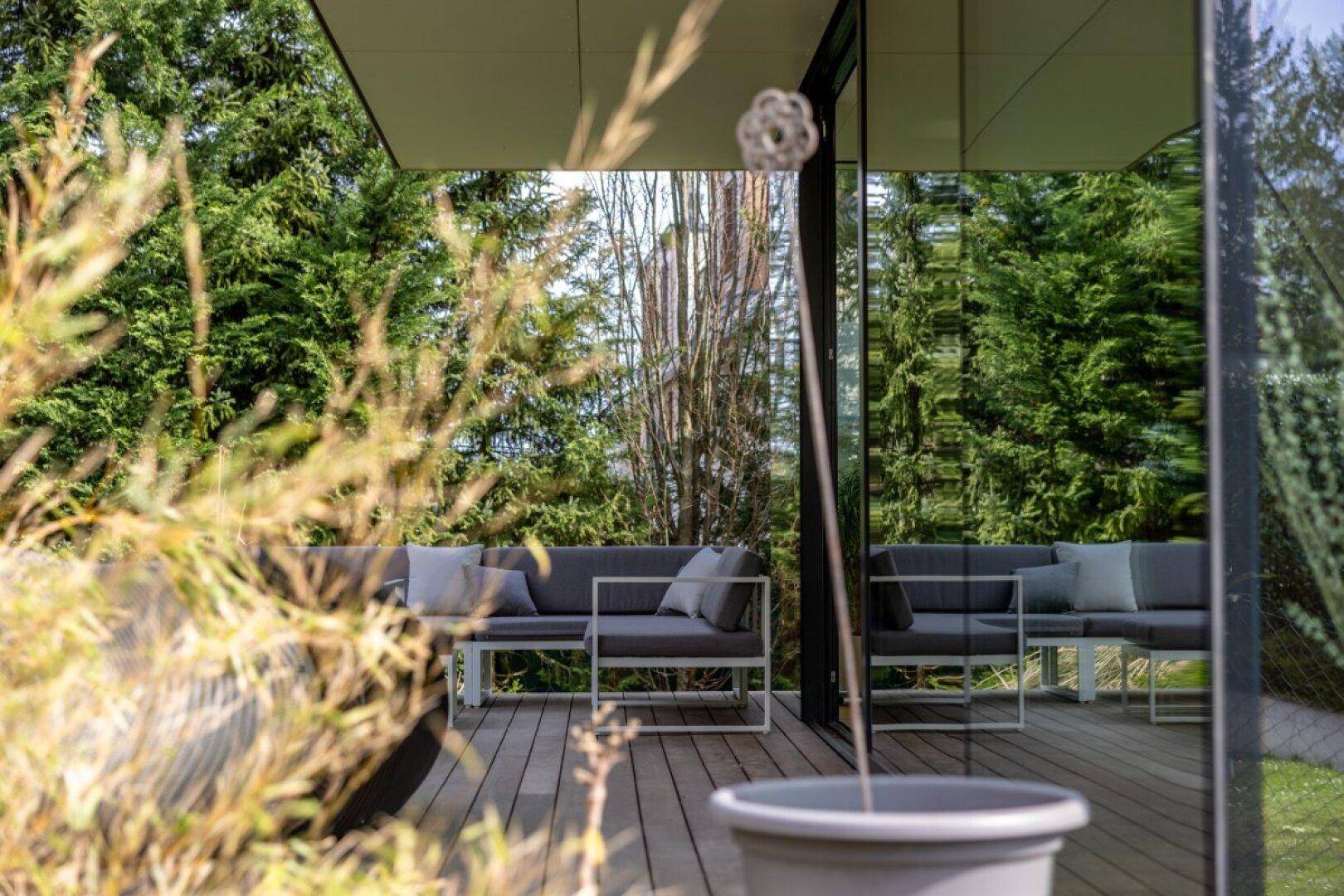 Gemütliche Terrasse mit modernen Outdoor-Möbeln, umgeben von üppigem Grün.