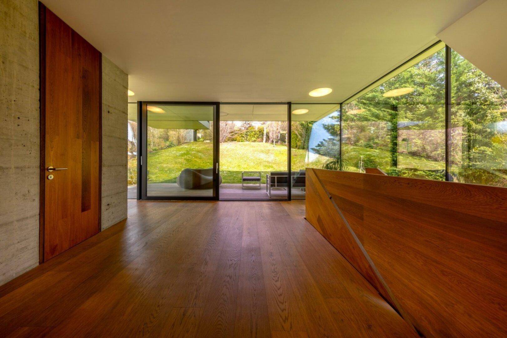 Heller Flur mit Holzboden, großen Glasfronten und direktem Zugang zum Garten.