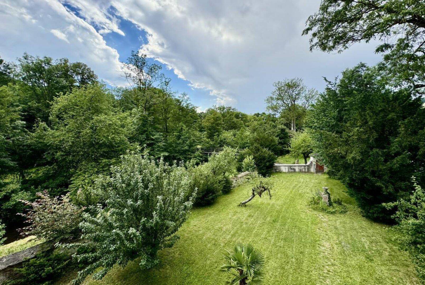 Panoramablick auf den weitläufigen Garten mit altem Baumbestand und gepflegtem Rasen.
