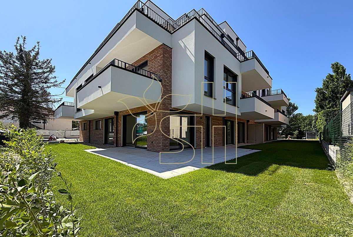 Moderne Wohnanlage mit weißer Fassade, Ziegelakzenten, Balkonen und gepflegter Rasenfläche.