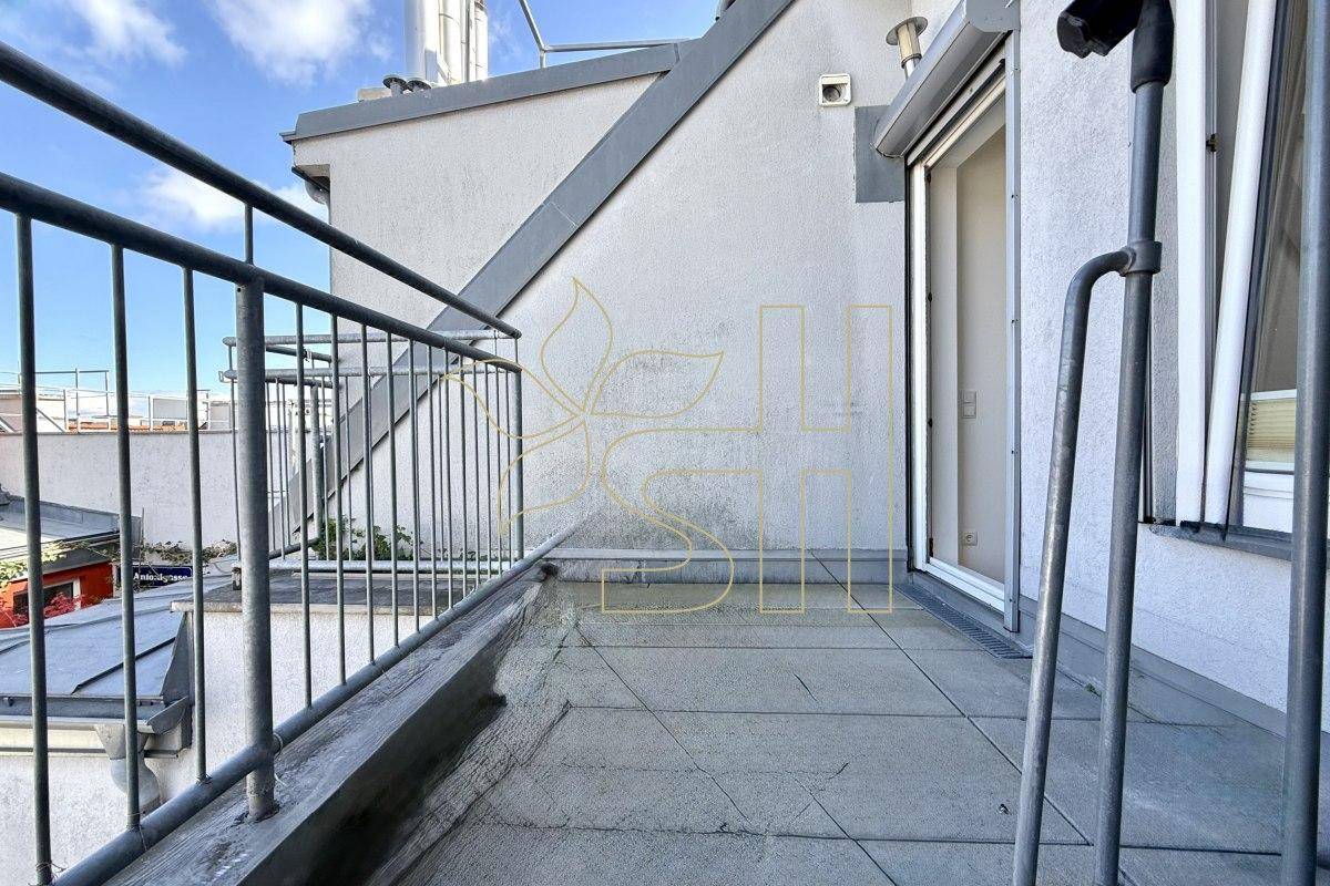 Kleiner Balkon mit Metallgeländer und Blick auf die umliegenden Dächer und Gebäude.