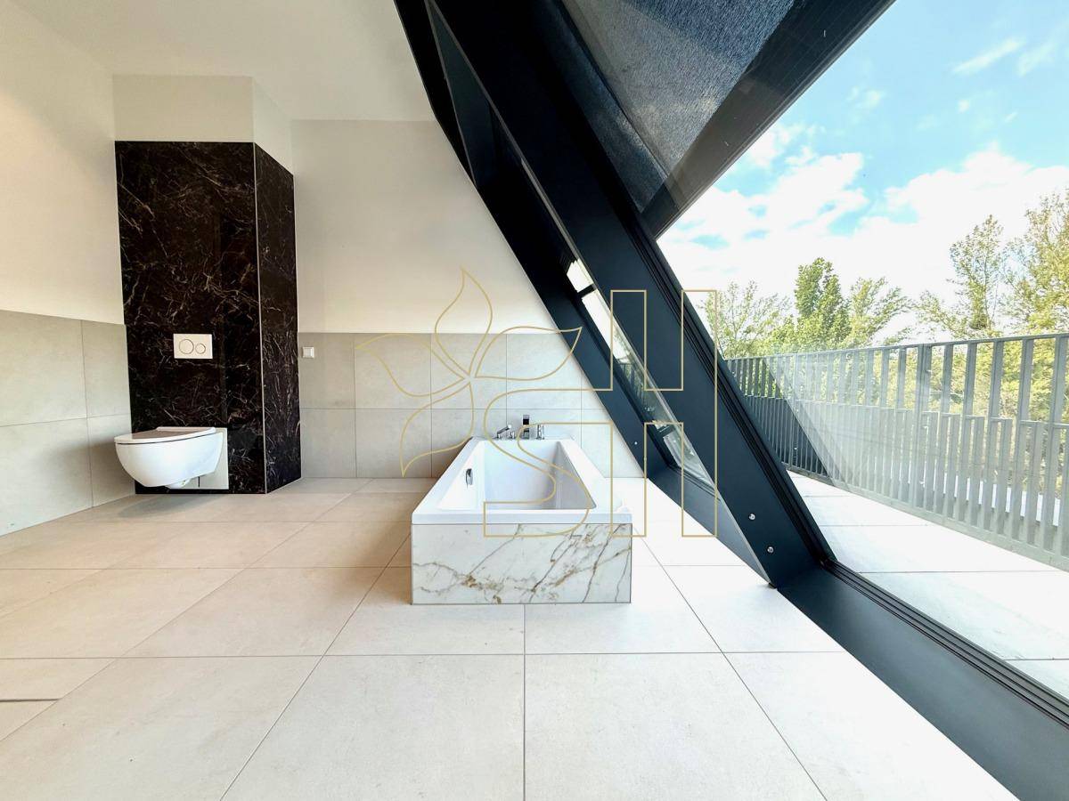 Modernes Badezimmer mit freistehender Badewanne, Marmorfliesen und großen Fenstern mit Ausblick.