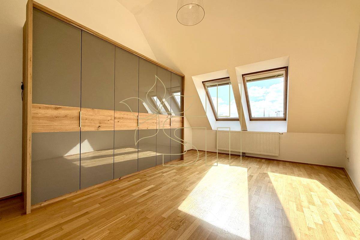 Schlafzimmer mit großem Einbauschrank, Holzparkett und zwei Dachfenstern für viel Licht.