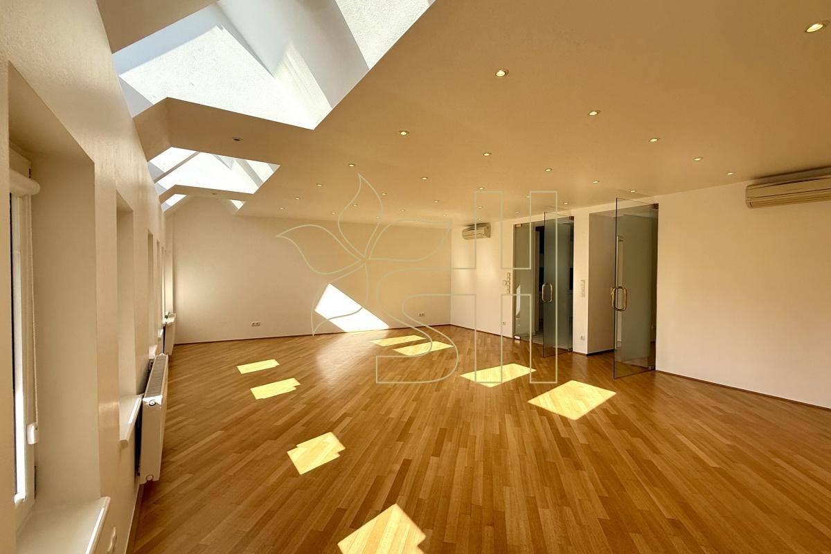 Lichtdurchfluteter Wohnraum mit Holzparkett, hohen Decken, Dachfenstern und Klimaanlage.