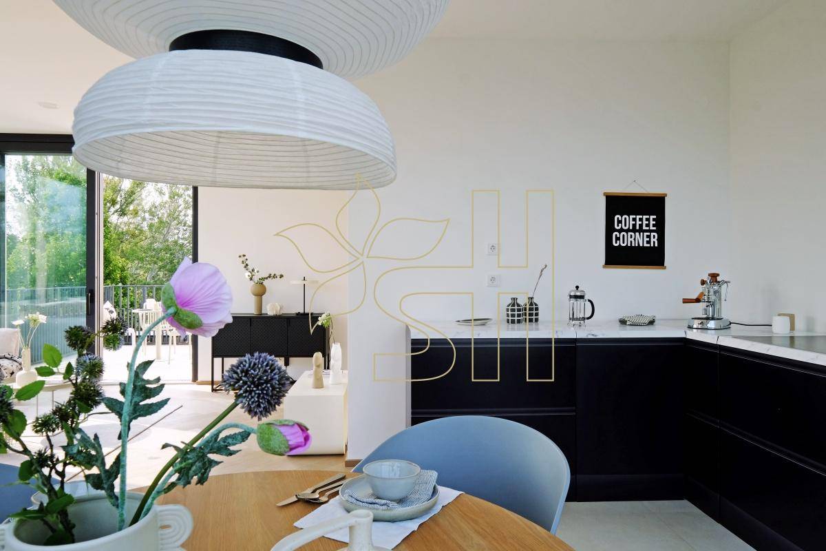 Moderne Küche mit schwarzer Arbeitsplatte und Essbereich, offen zum Wohnzimmer und mit Terrassenzugang.