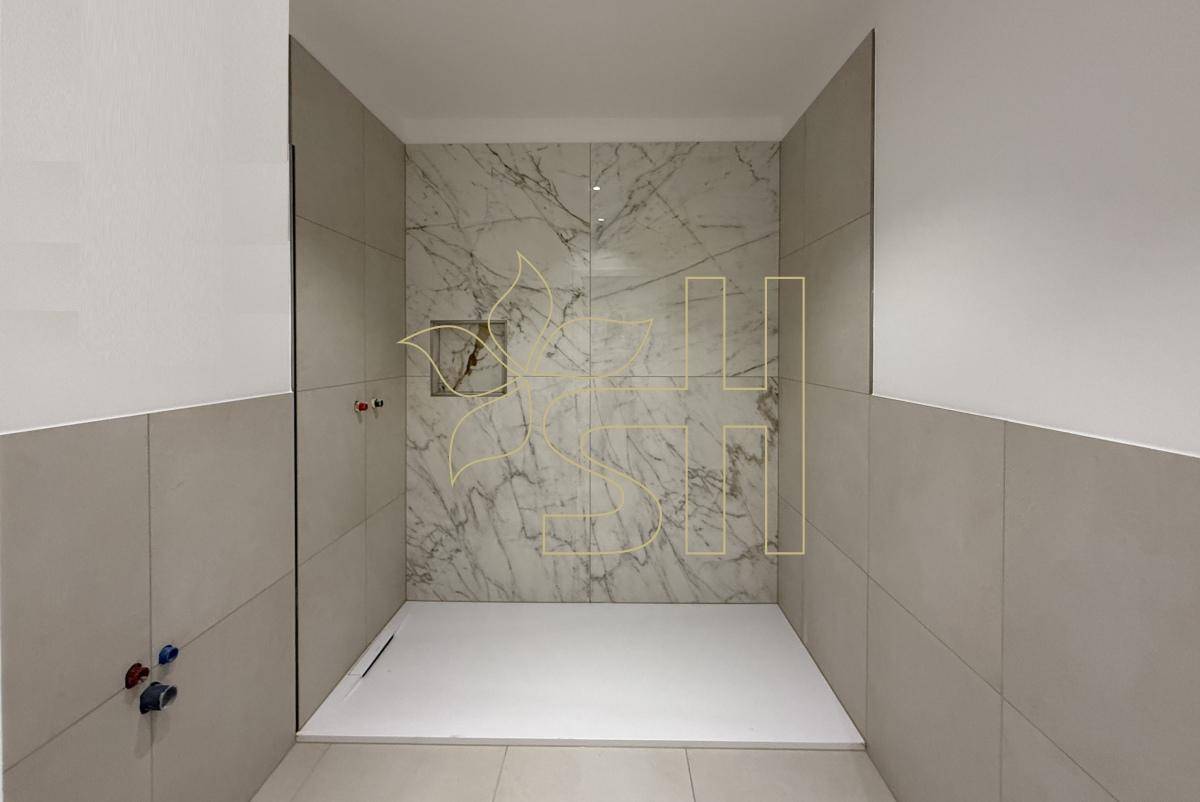 Moderne begehbare Dusche mit stilvollen Marmorfliesen und einem minimalistischen Design.