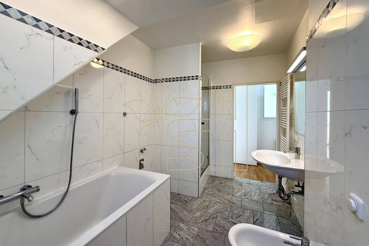 Badezimmer mit Badewanne, Waschbecken, Bidet und Fliesenboden in hellem Design.