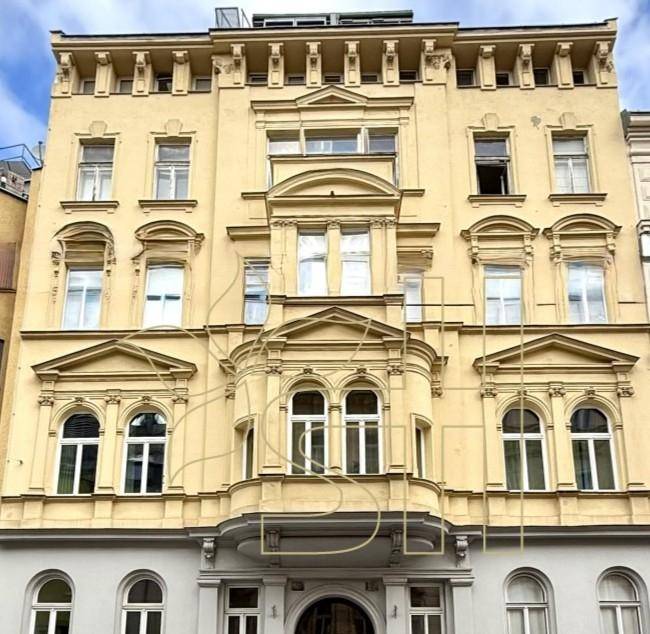 Historische Fassade eines Altbaus mit reich verzierten Fenstern und klassischer Architektur.