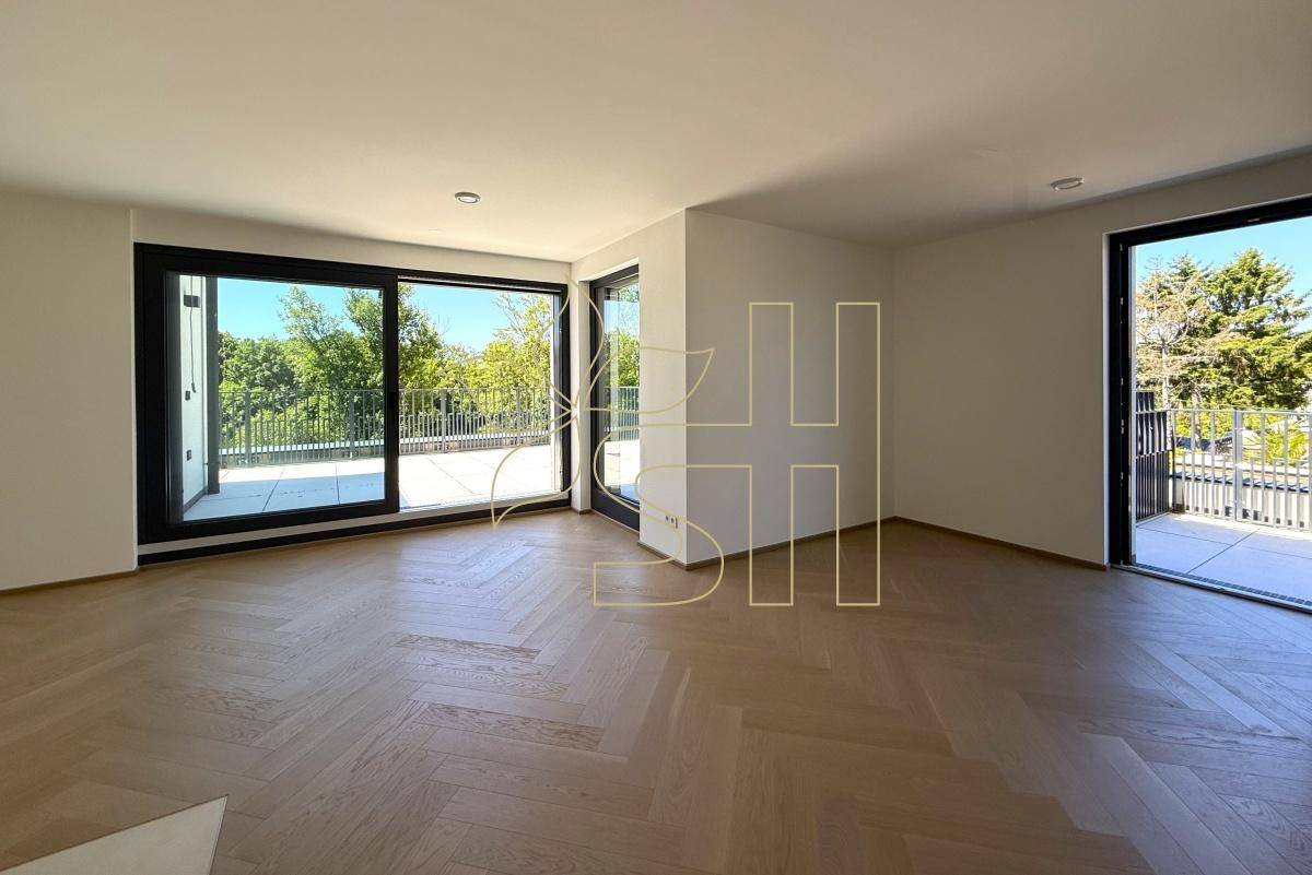 Lichtdurchfluteter Wohnraum mit elegantem Parkettboden und mehreren Zugängen zu einer weitläufigen Außenterrasse.
