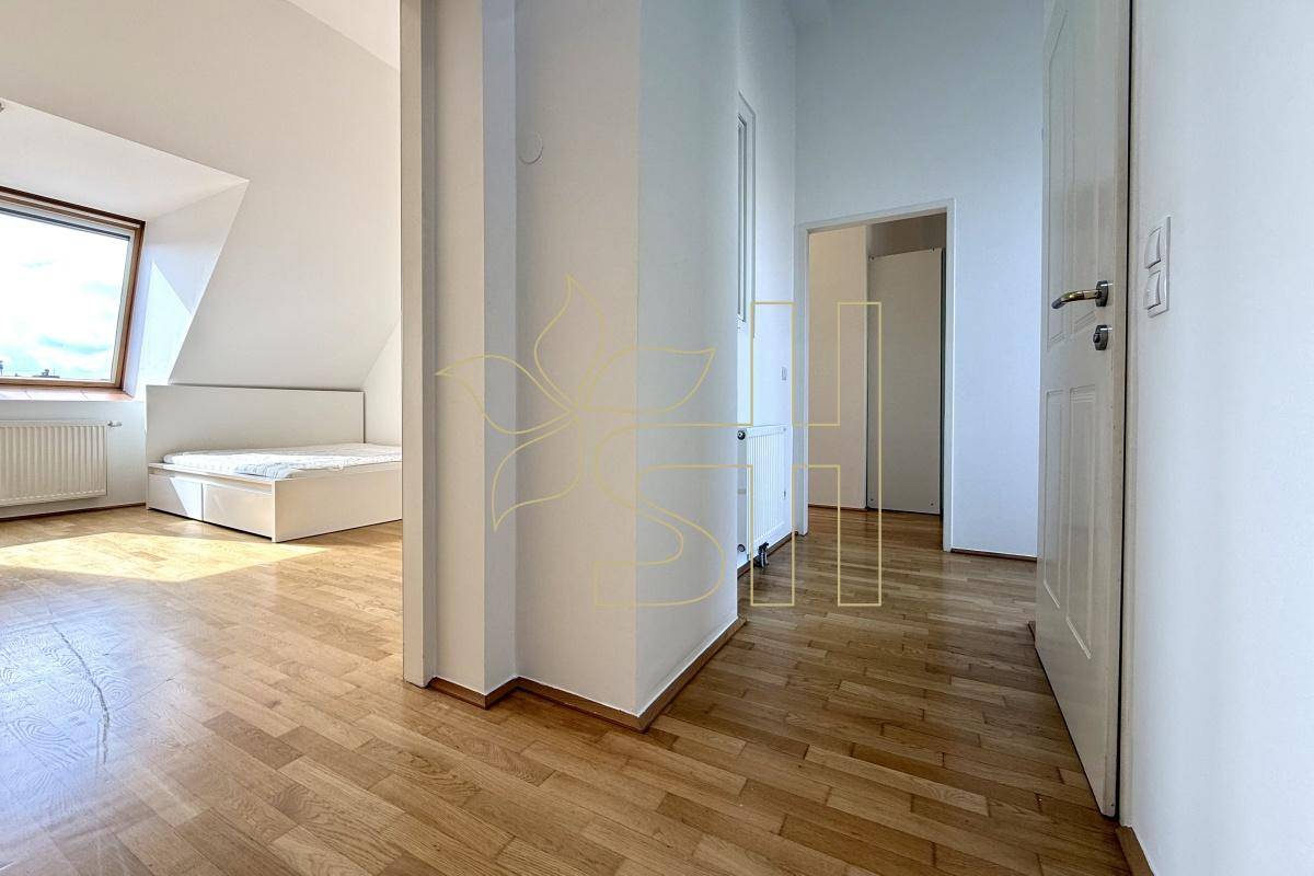 Schlafzimmer mit hellem Holzparkett, Dachschrägen und natürlichem Lichteinfall durch die Fenster.