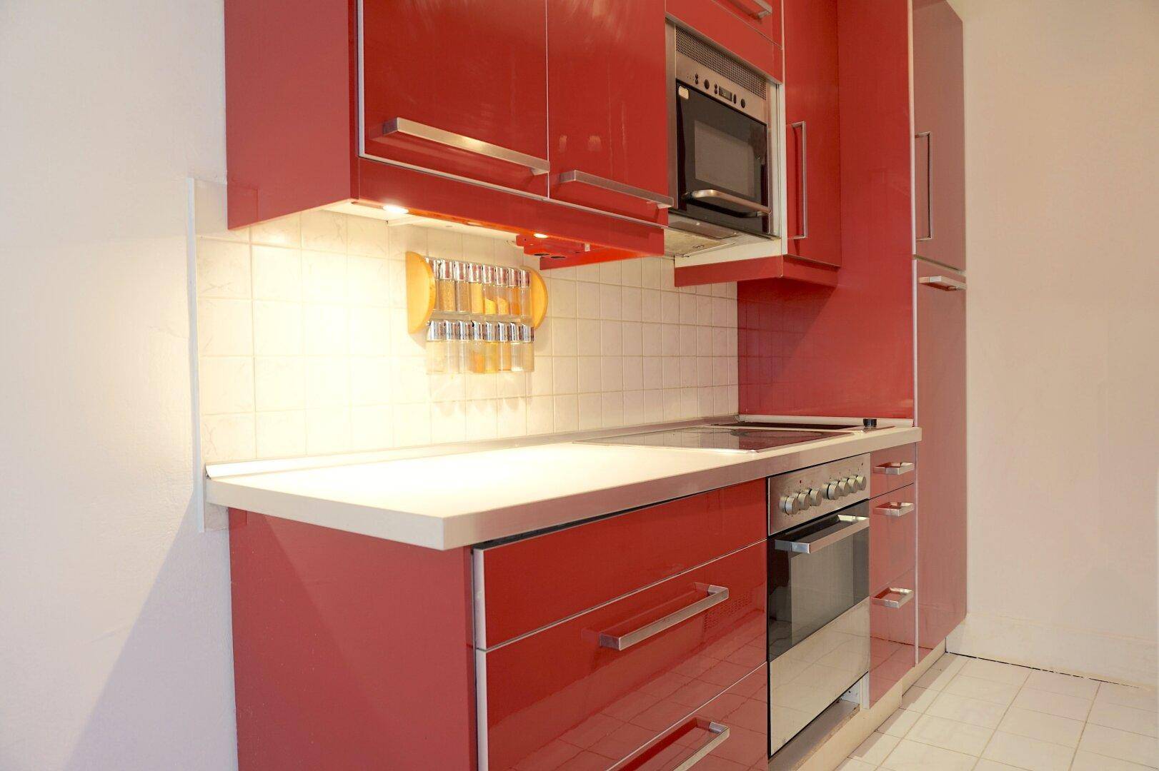 Detailansicht der modernen roten Einbauküche mit integriertem Backofen und Mikrowelle.