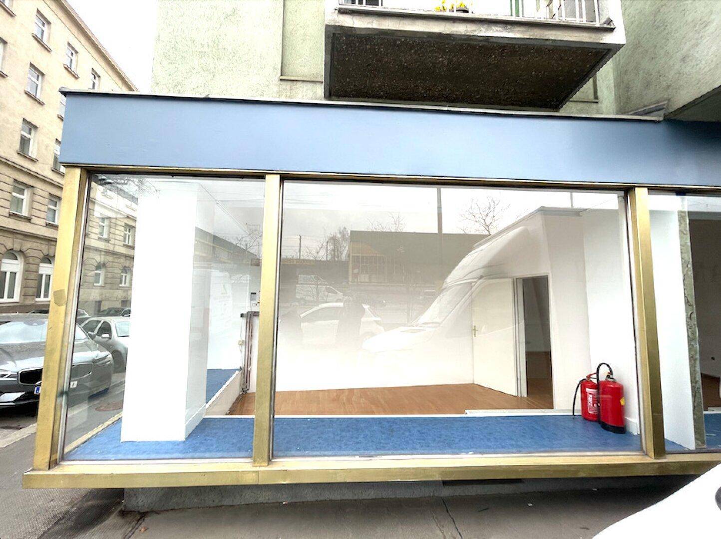 Schaufensterfront eines Geschäfts mit goldfarbenen Rahmen und blauer Akzentleiste an der Fassade.