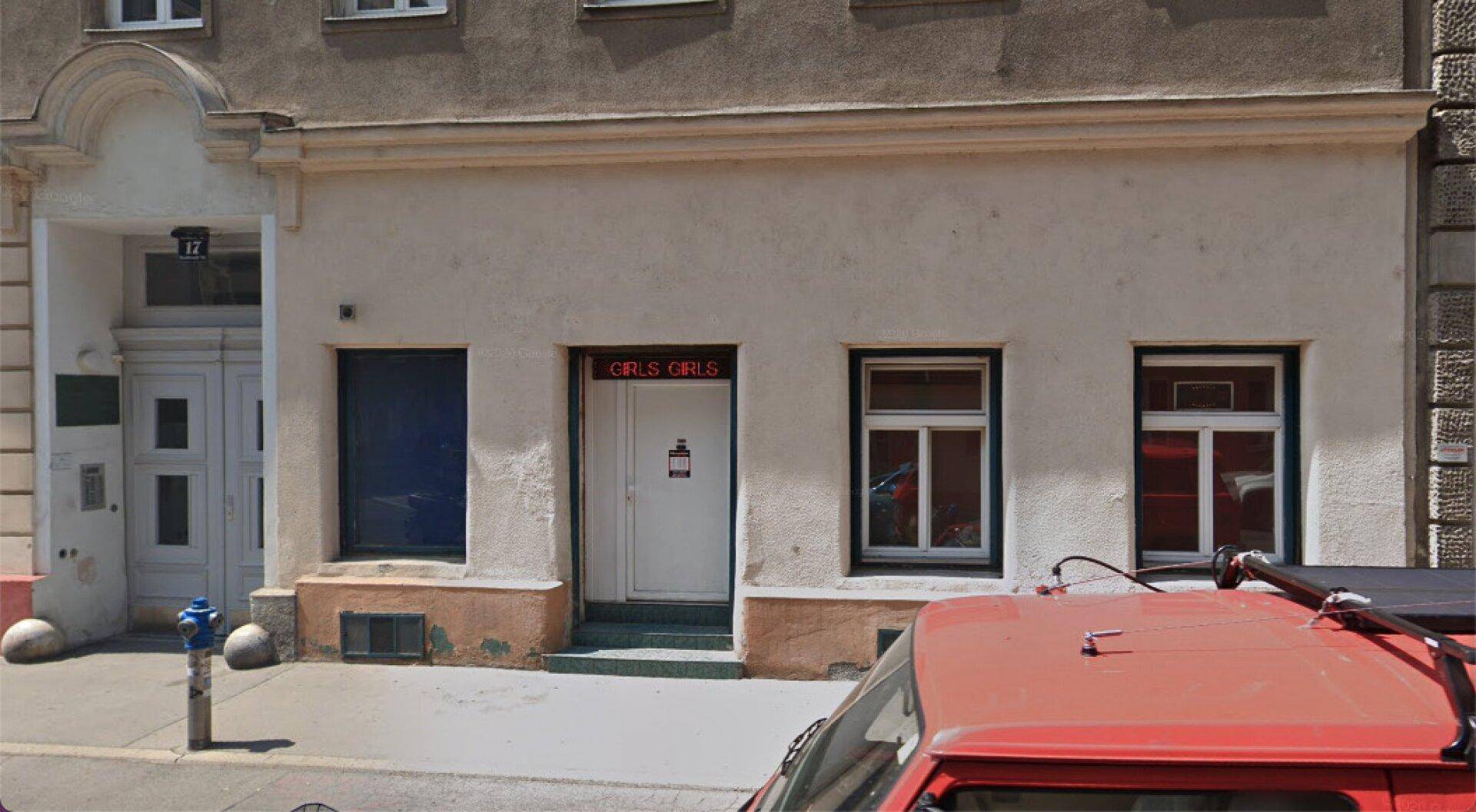Fassade eines Gebäudes mit zwei Fenstern und einem Eingang, der zu einem Geschäft führt.