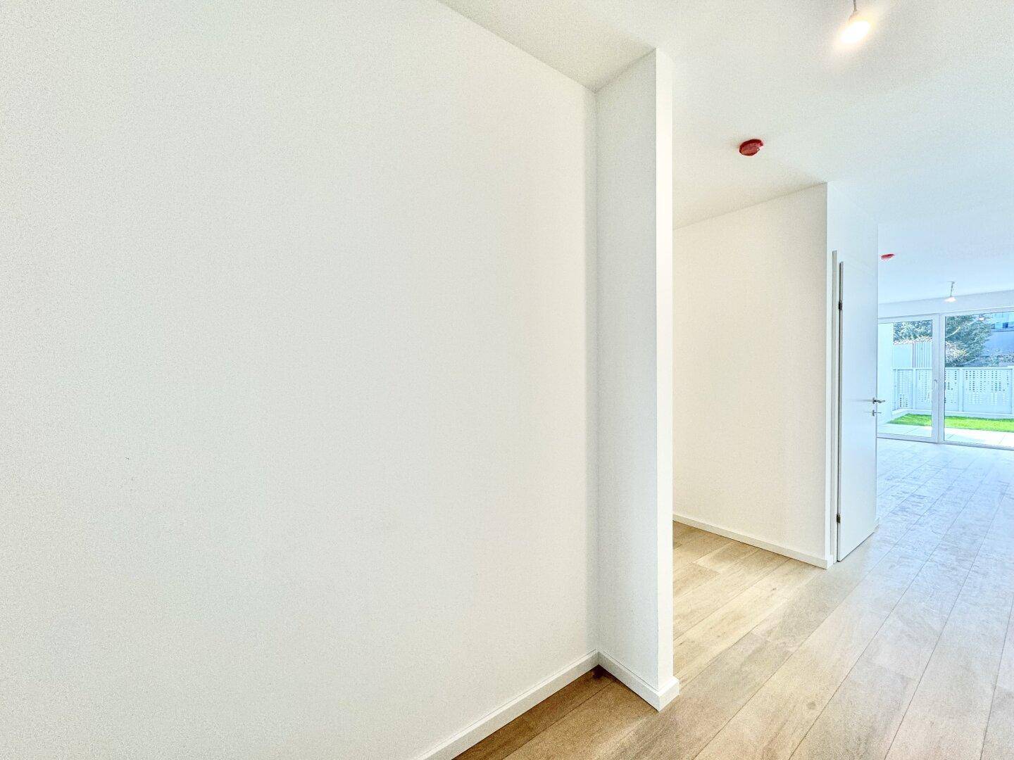 Moderner Flur mit hellem Holzboden und weiß gestrichenen Wänden.