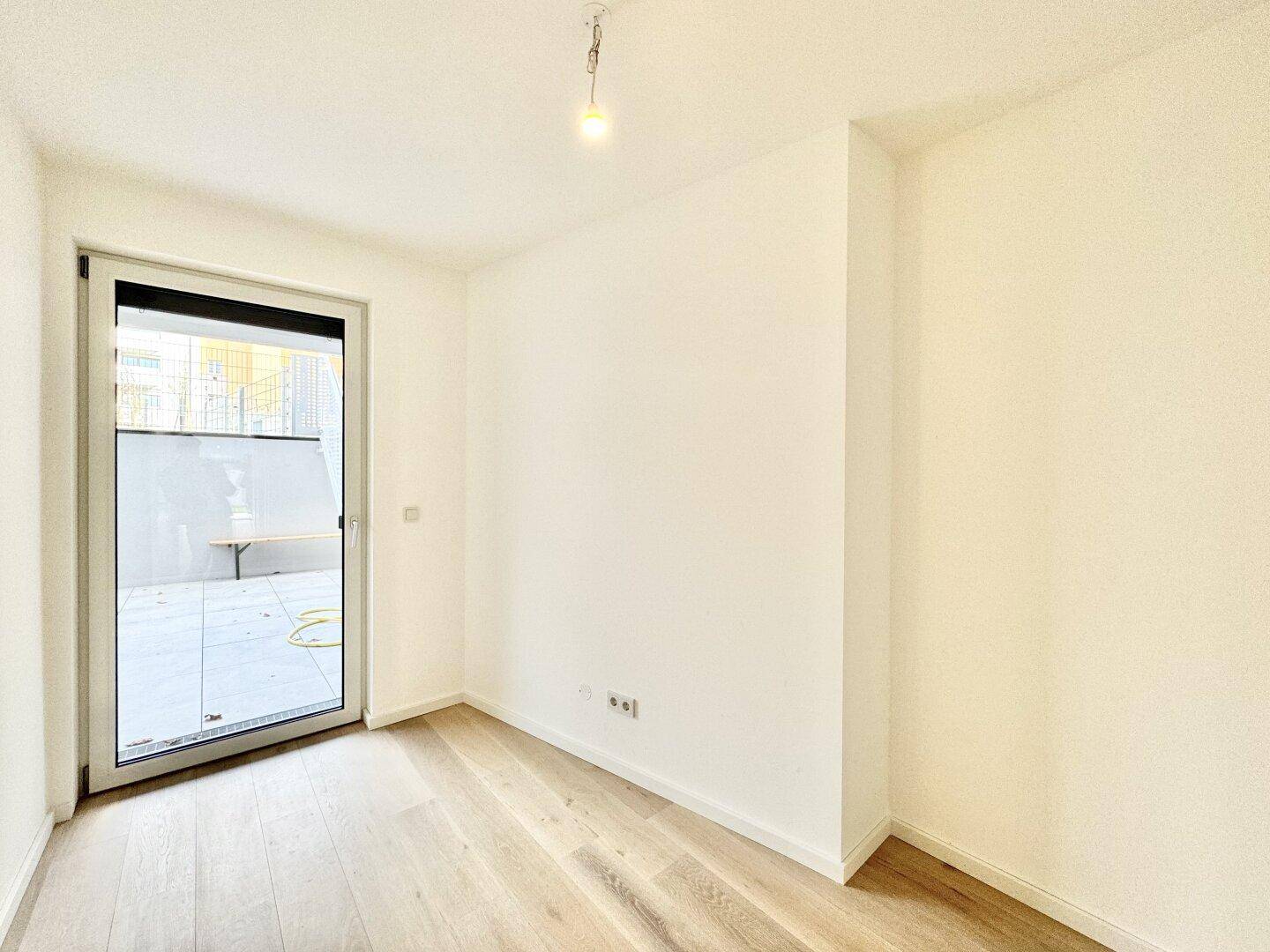 Helles Schlafzimmer mit Holzboden und Zugang zu einem kleinen Außenbereich.