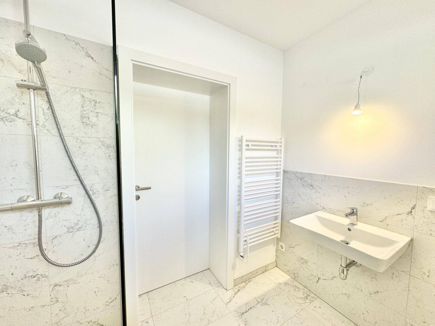 Modernes Badezimmer mit Waschbecken, Dusche und beheiztem Handtuchhalter.