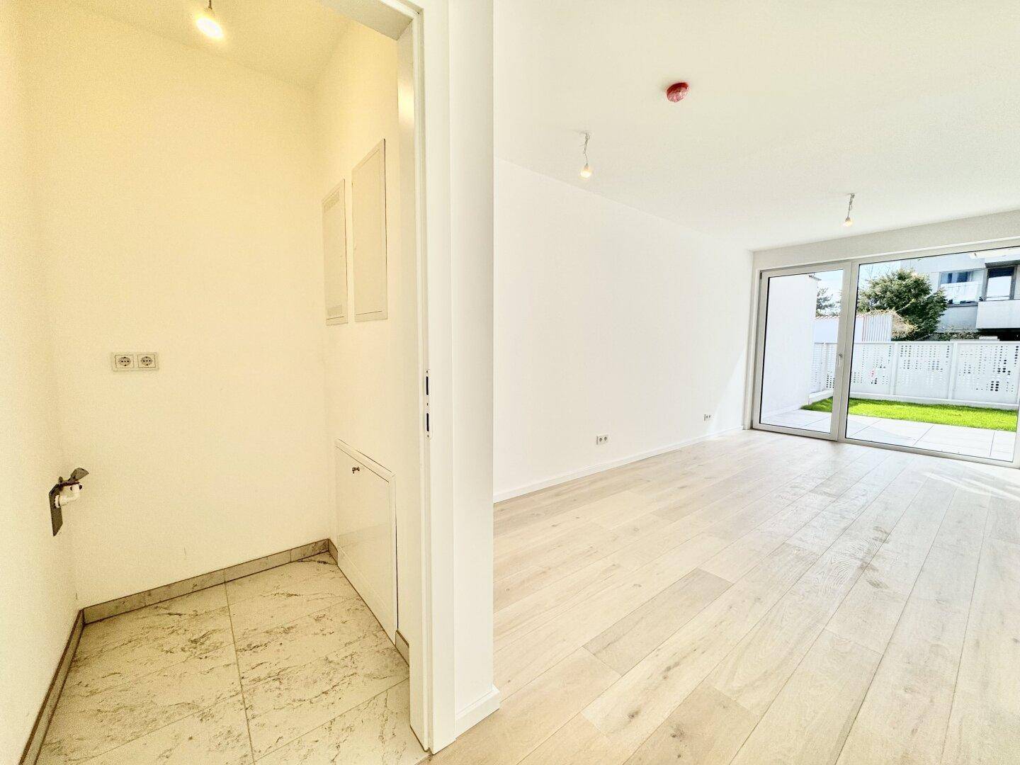 Heller Eingangsbereich mit Holzboden und angrenzendem Fliesenbereich für Anschlüsse.