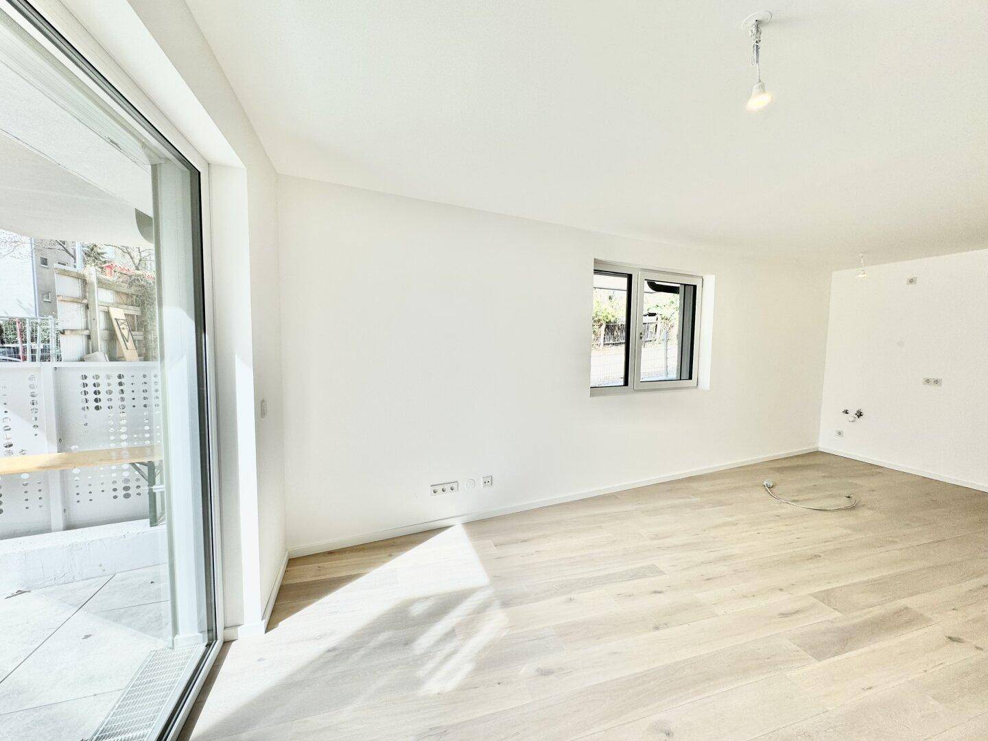 Geräumiges Zimmer mit großen Fenstern und hellem Holzboden, bereit zur Einrichtung.