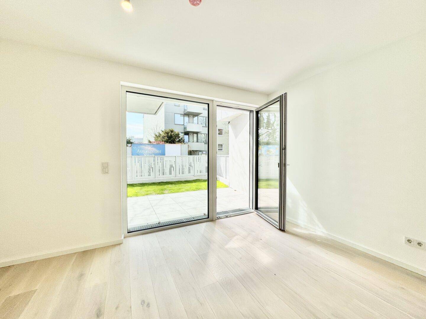 Heller Wohnraum mit hellem Holzparkett und Zugang zur Terrasse und zum Garten.
