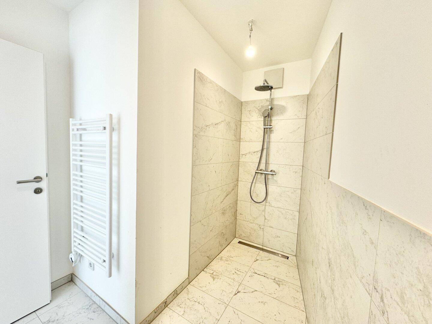 Helles Badezimmer mit moderner Dusche, Waschbecken und praktischem Handtuchheizkörper.
