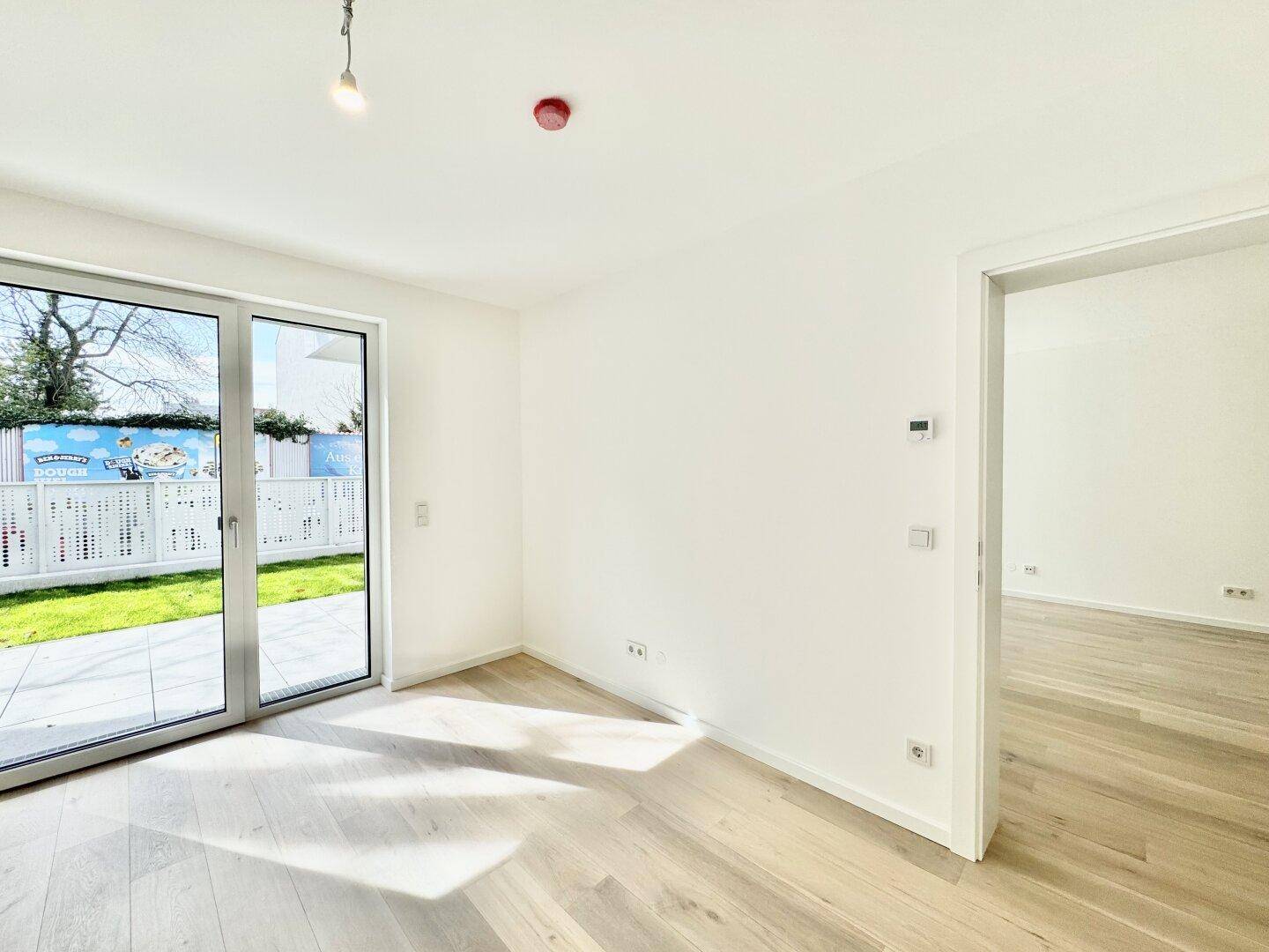 Lichtdurchfluteter Raum mit Holzboden und direktem Zugang zum privaten Gartenbereich.