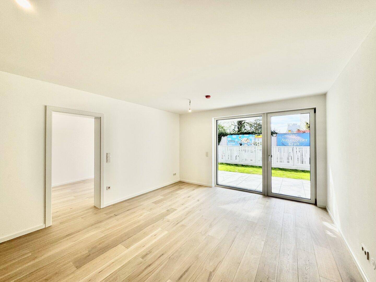 Geräumiger, heller Wohnbereich mit Holzboden und Blick auf den privaten Garten.