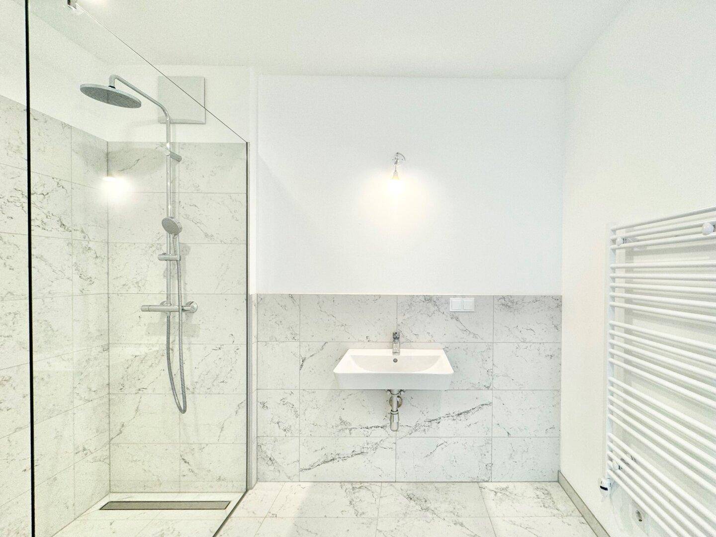 Modernes Badezimmer mit begehbarer Dusche, Marmorfliesen und beheiztem Handtuchhalter.
