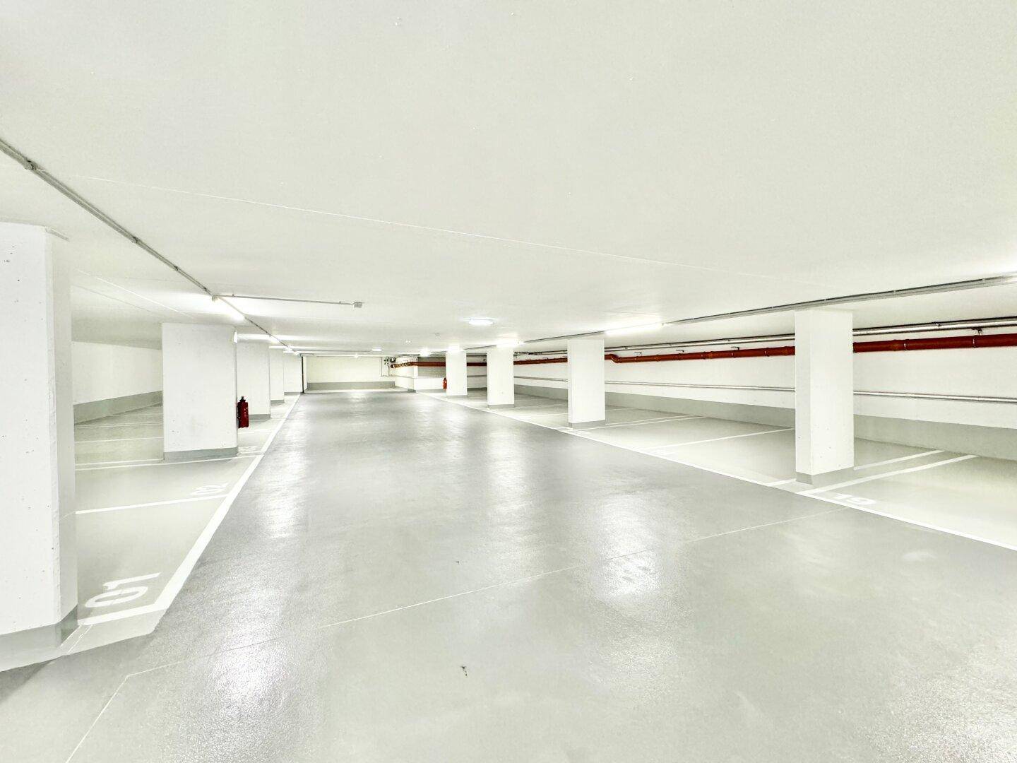 Eine geräumige, leere Tiefgarage mit vielen Parkplätzen und klaren Markierungen.