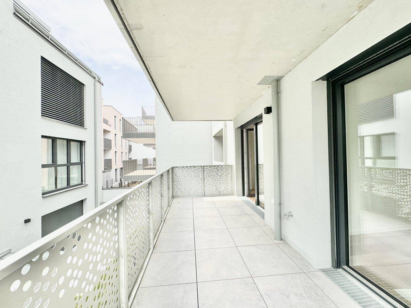 Langer, gefliester Balkon mit modernem Geländer und Zugang zu den Innenräumen.